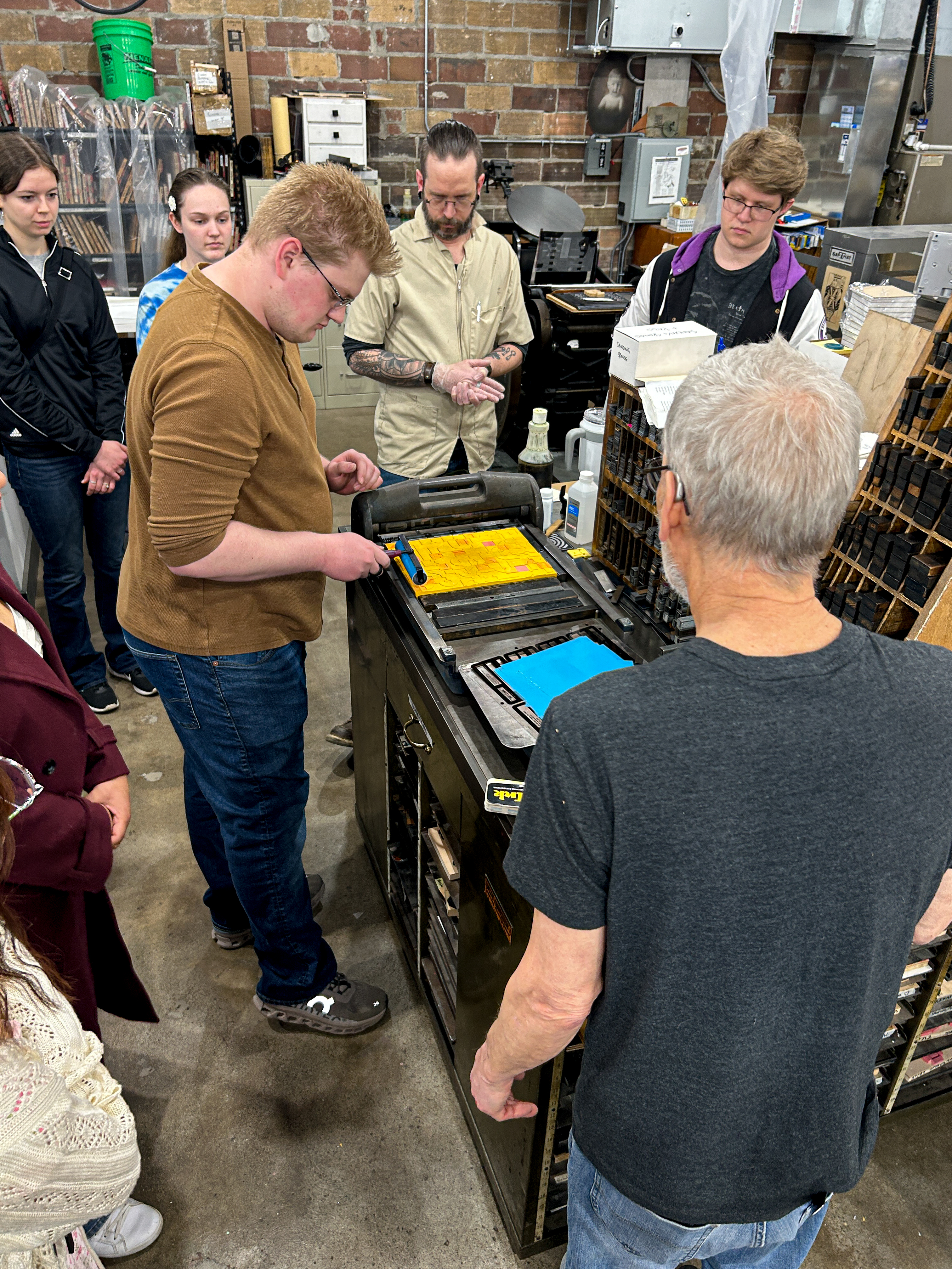 DAD student inks the raised surfaces as classmates watch during the letterpress workshop.